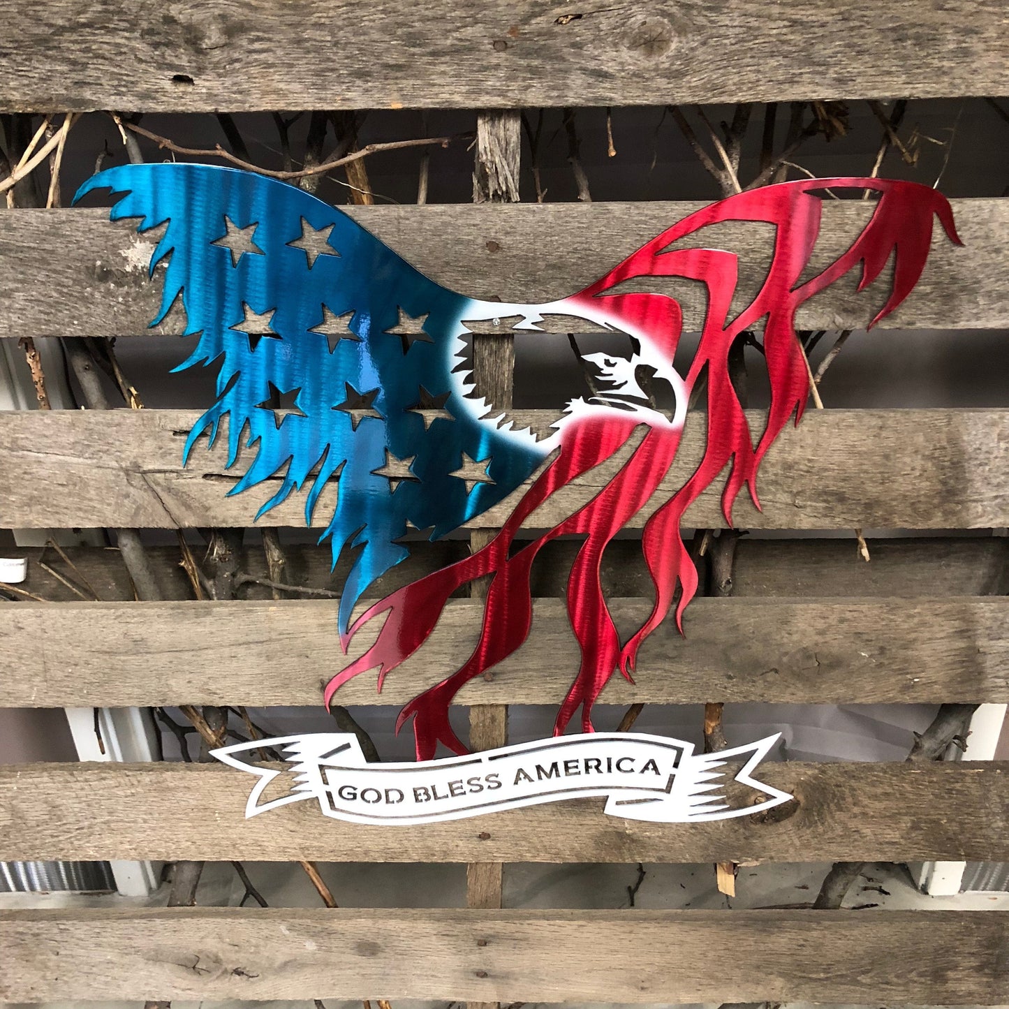 Metal wall art of an American flag with 'God Bless America' on a wooden background
