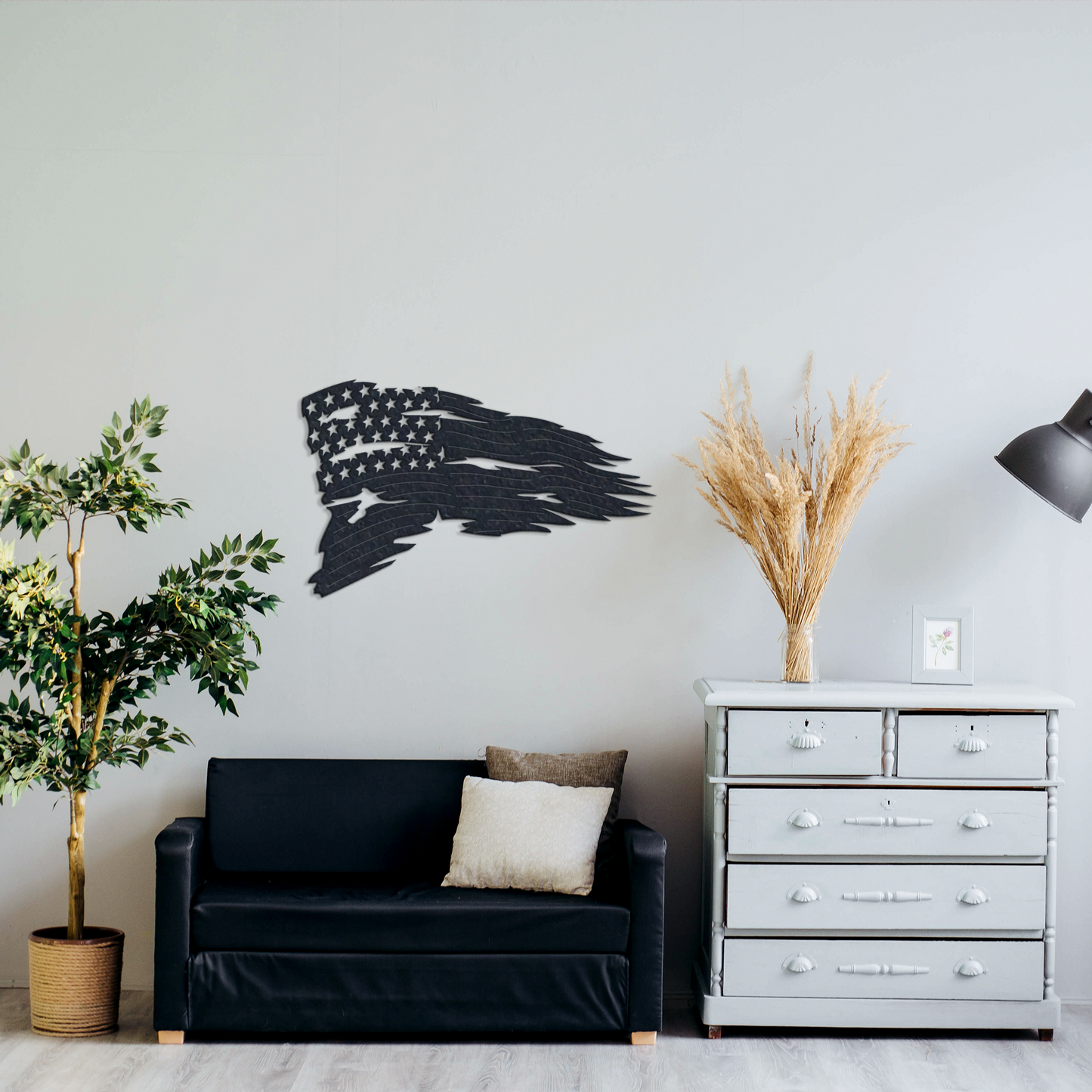 Living room with black sofa, decorative plant, and wall art of an American flag.