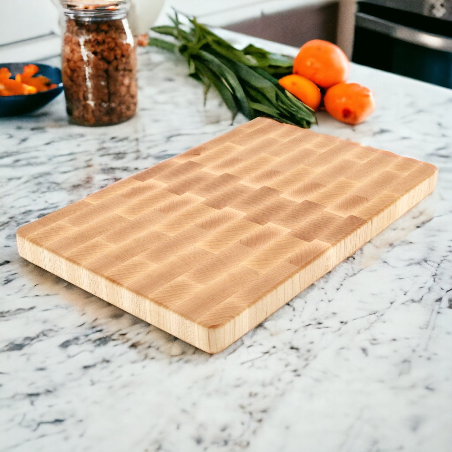 Wooden cutting board on a marble countertop with oranges and other items in the background.