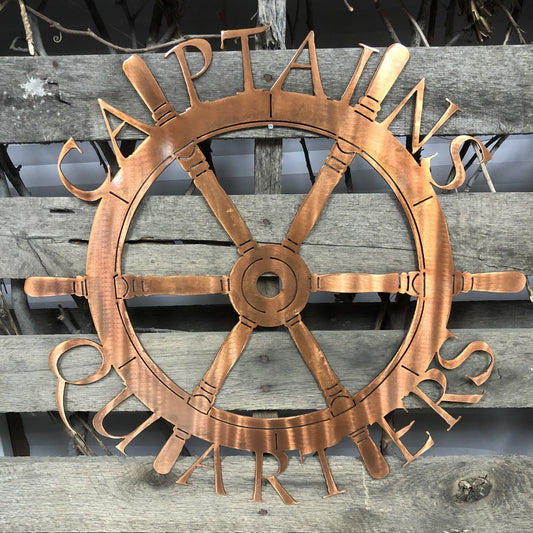 Copper ship's wheel decorative wall art on a wooden background  Captain's Quarters