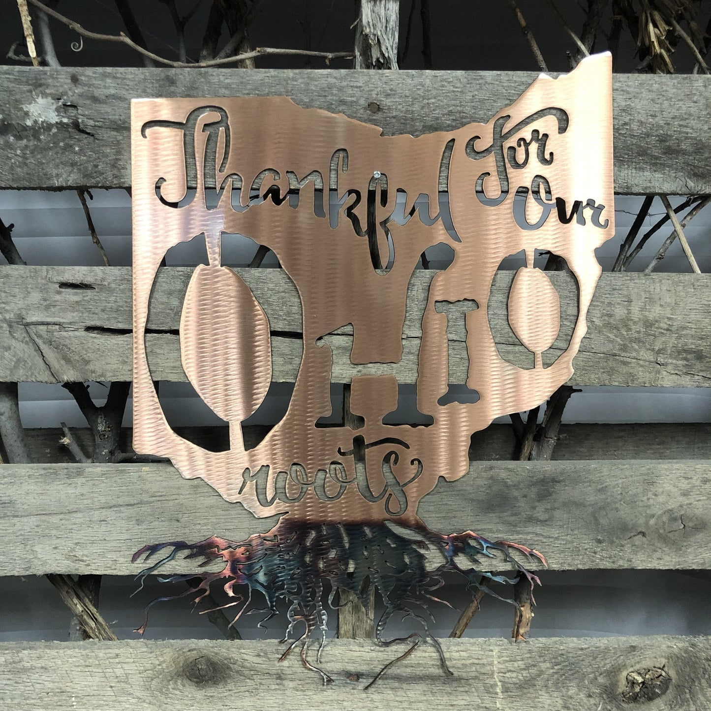Metal sign with 'Thankful for our wolves' text on a wooden surface