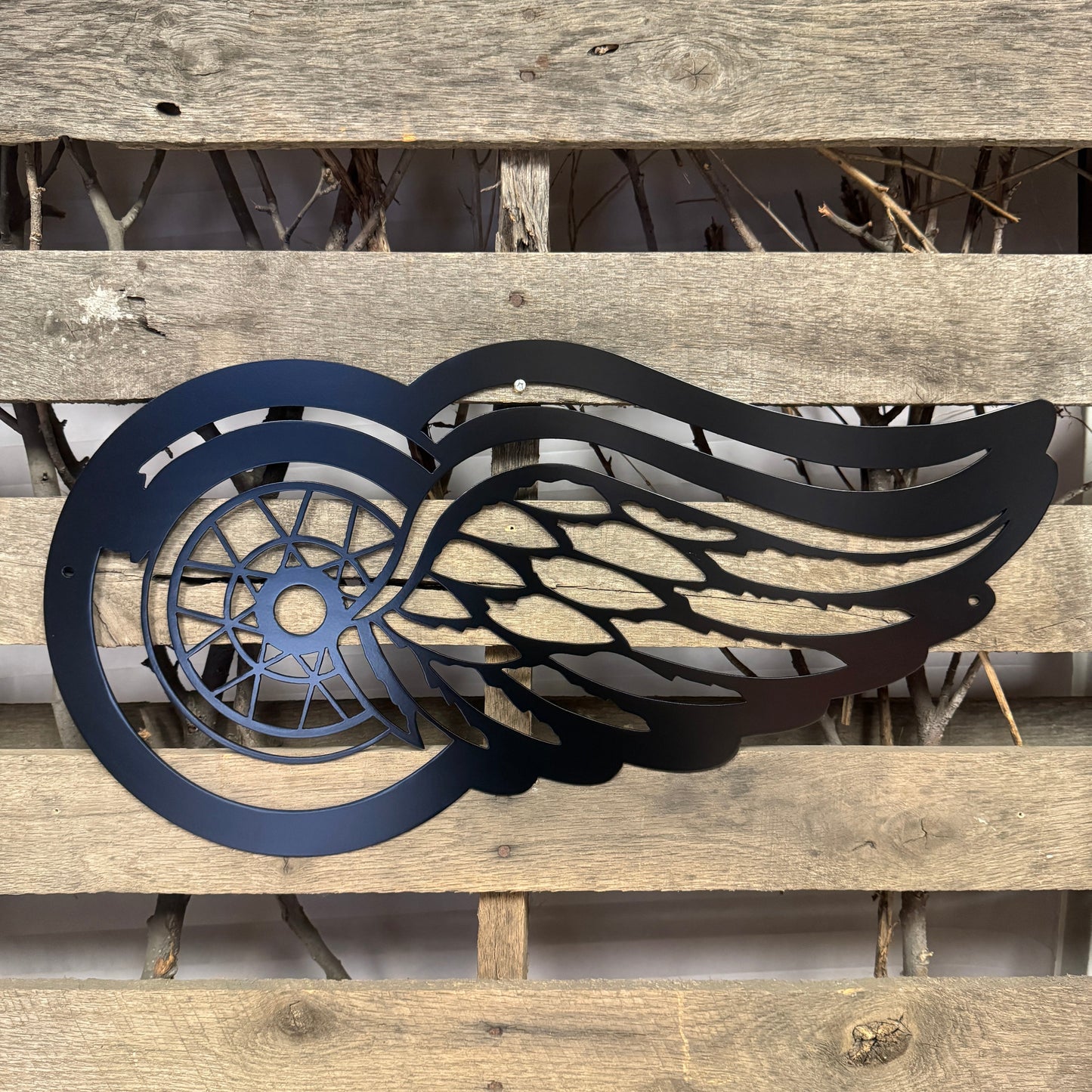 Black Detroit Redwinged metal winged symbol on a wooden background