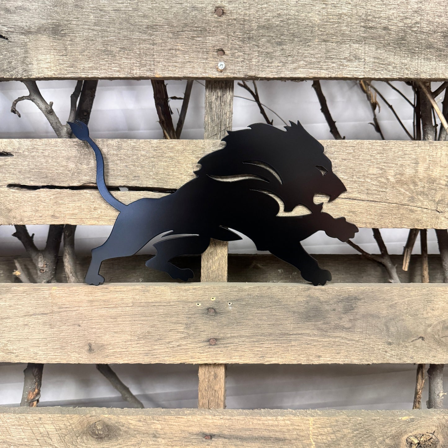 Black metal lion sculpture on a wooden pallet