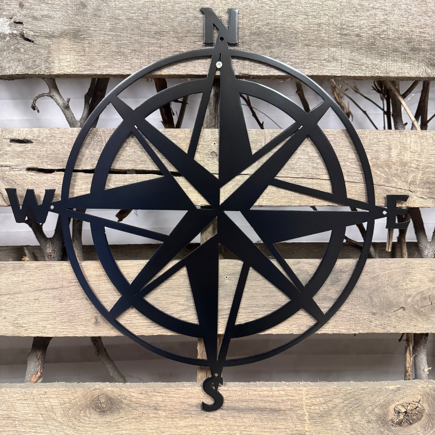 Black compass wall decor on a wooden surface