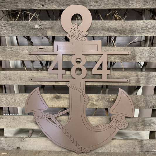 Decorative metal anchor with numbers '484' on a wooden background