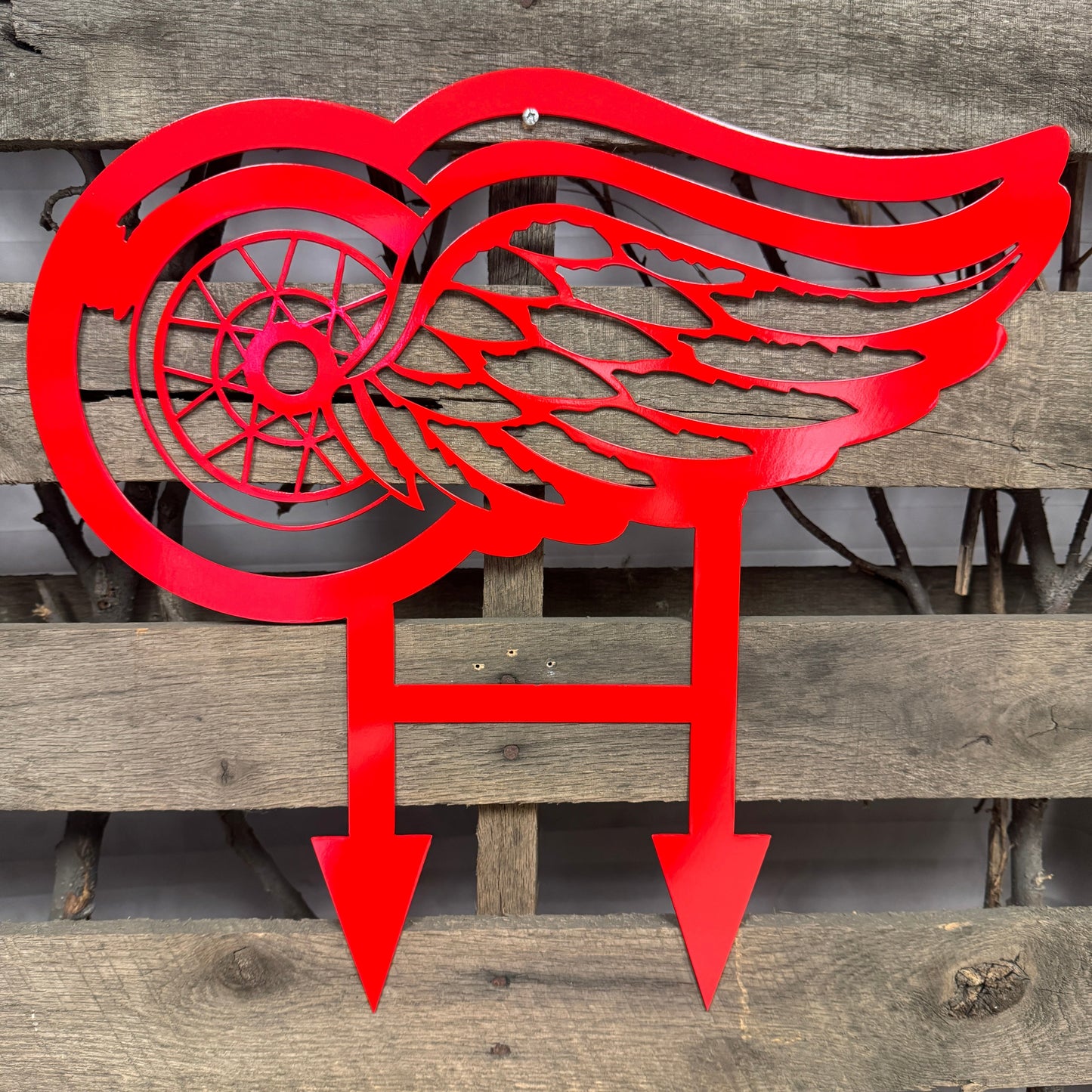 Red metal winged logo on a wooden background