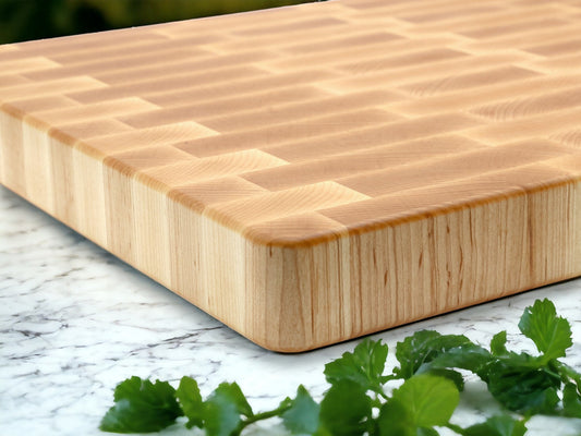 Wooden cutting board on a marble surface with fresh green herbs.