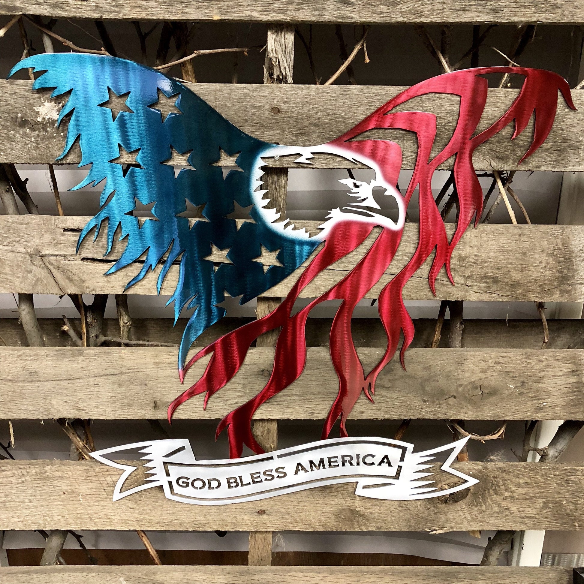 Metal art of an American flag with 'God Bless America' banner on wooden background