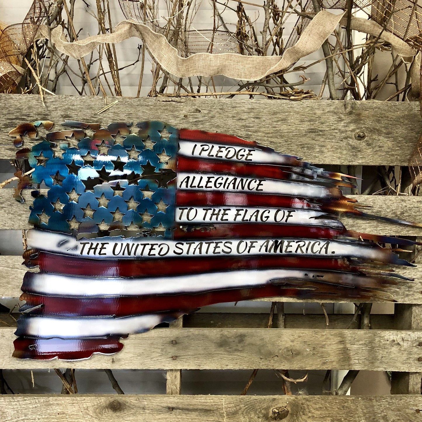 Metallic American flag with engraved Pledge of Allegiance on a wooden surface.