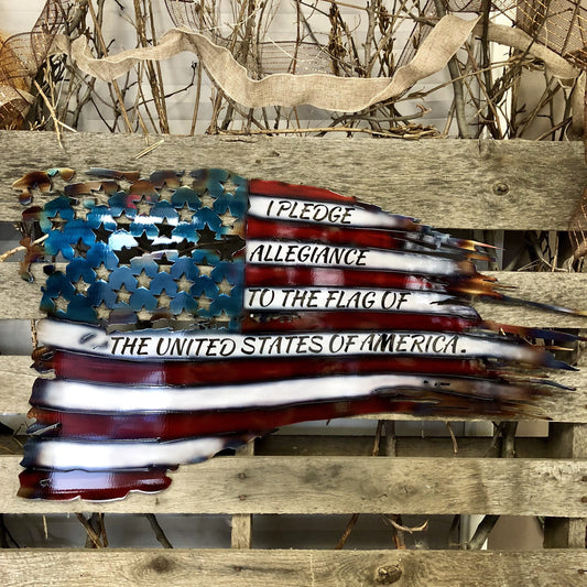 Metallic American flag with engraved Pledge of Allegiance on a wooden surface.