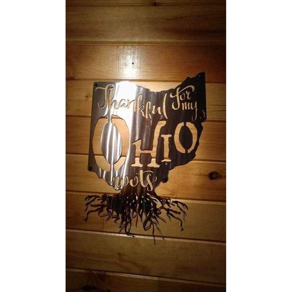 Metal wall art shaped like the state of Ohio with text on a wooden background